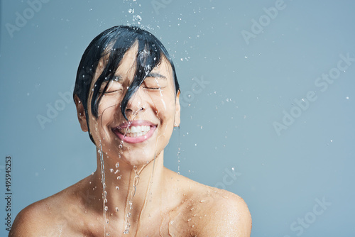 Wake up to the refreshing sensation of water. Shot of a young woman having a refreshing shower against a blue background.