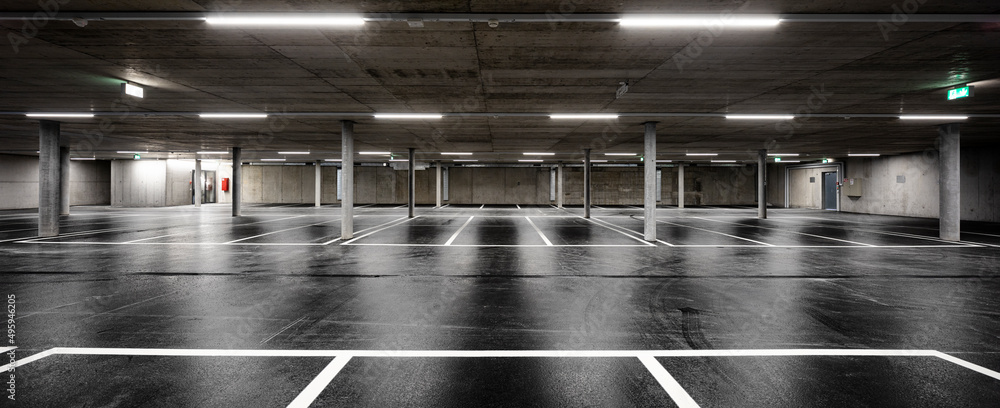 Front view of new empty underground parking with concrete columns, shiny asphalt and nobody inside - obrazy, fototapety, plakaty 