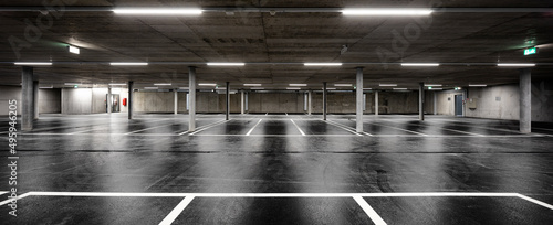 Front view of new empty underground parking with concrete columns, shiny asphalt and nobody inside photo