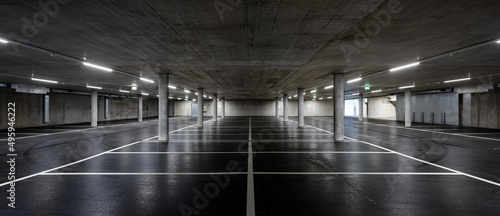 Картината върху платно Front view of new empty underground parking with concrete columns, shiny asphalt