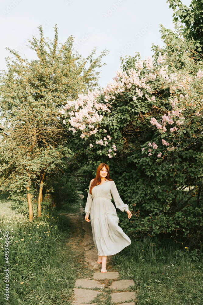 young woman plus size model walking in park next to blooming lilac tree, concept of spring, vertical photo, golden hour, barefoot young woman plus size model walking in park next to blooming lilac tree, concept of spring, vertical photo, golden hour, barefoot
