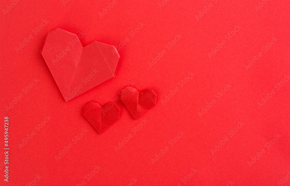 Red origami hearts on red background