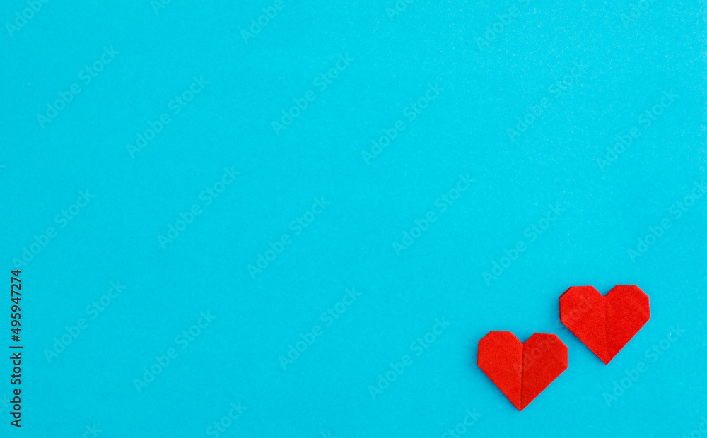 Red origami hearts on blue background