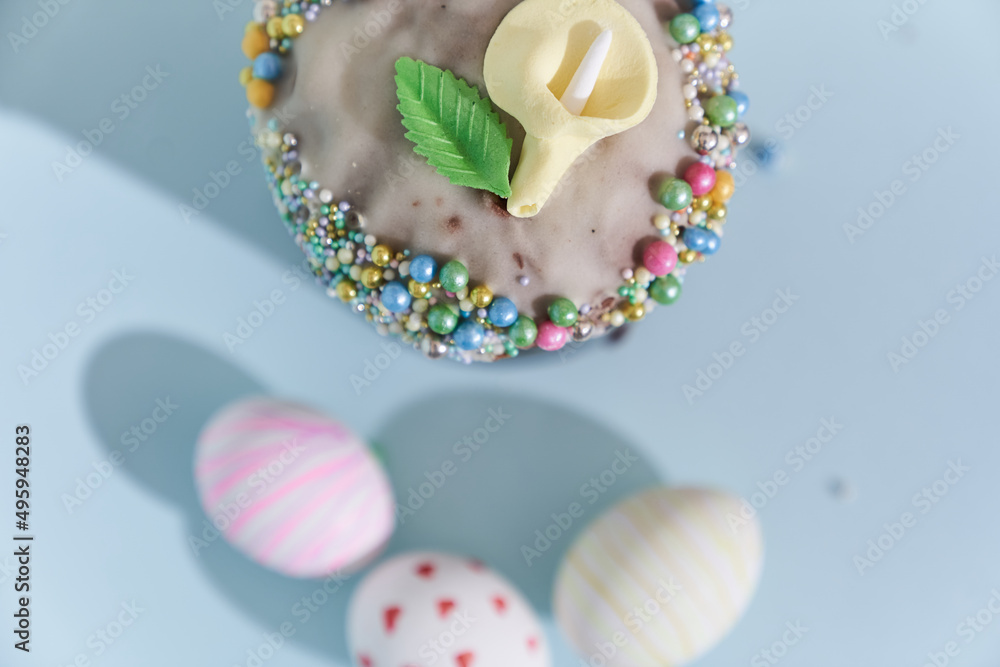 Close-up of three white Easter eggs with a pattern in the form of hearts and waves and a cake with a flower decoration. Orthodox Easter on a blue background top view. High quality photo Close-up of three white Easter eggs with a pattern in the form of hearts and waves and a cake with a flower decoration. Orthodox Easter on a blue background top view. High quality photo