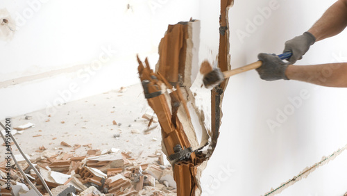 Man hitting a brick wall with a hammer, wall demolition