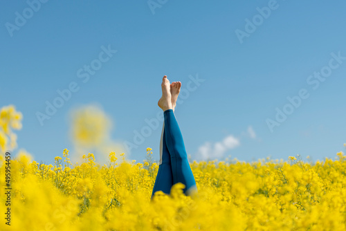 Photography woman wearing blue leggings doing a headstand in a yellow field
