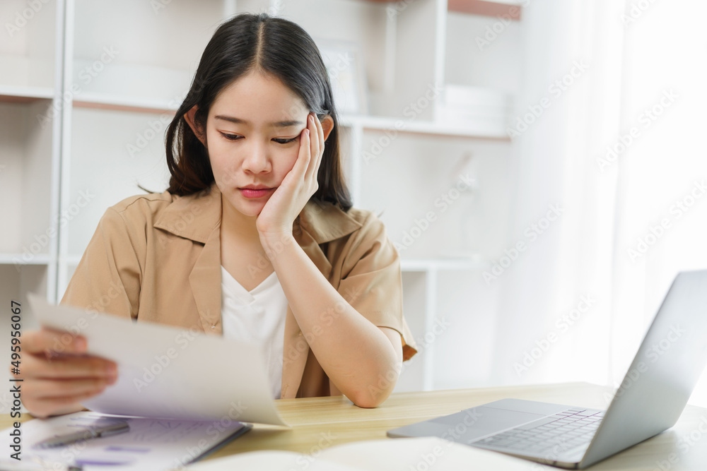 Online lifestyle concept A female home worker seriously concentrating on reading some data from the paper . Online lifestyle concept A female home worker seriously concentrating on reading some data from the paper .