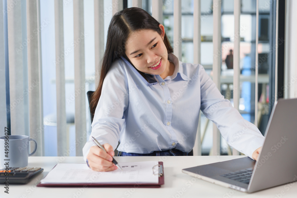 Business concept, Businesswoman talking with client on smartphone and taking notes data on document Business concept, Businesswoman talking with client on smartphone and taking notes data on document