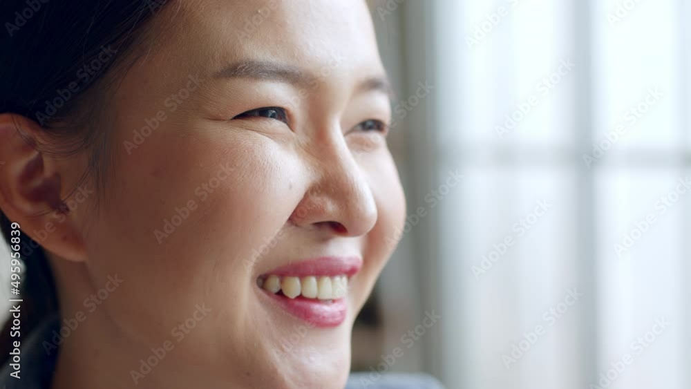 Close up of young Asian woman face with smile at window Close up of young Asian woman face with smile at window