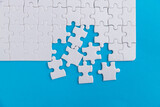 Unfinished white puzzle pieces on blue background