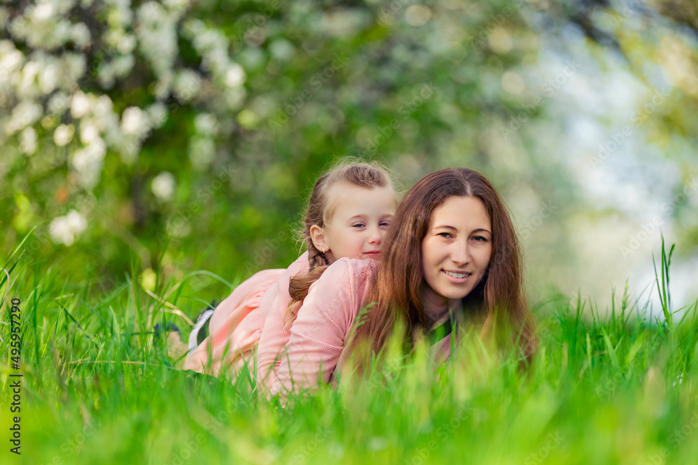 mother and daughter in identical dresses lie in the grass mother and daughter in identical dresses lie in the grass