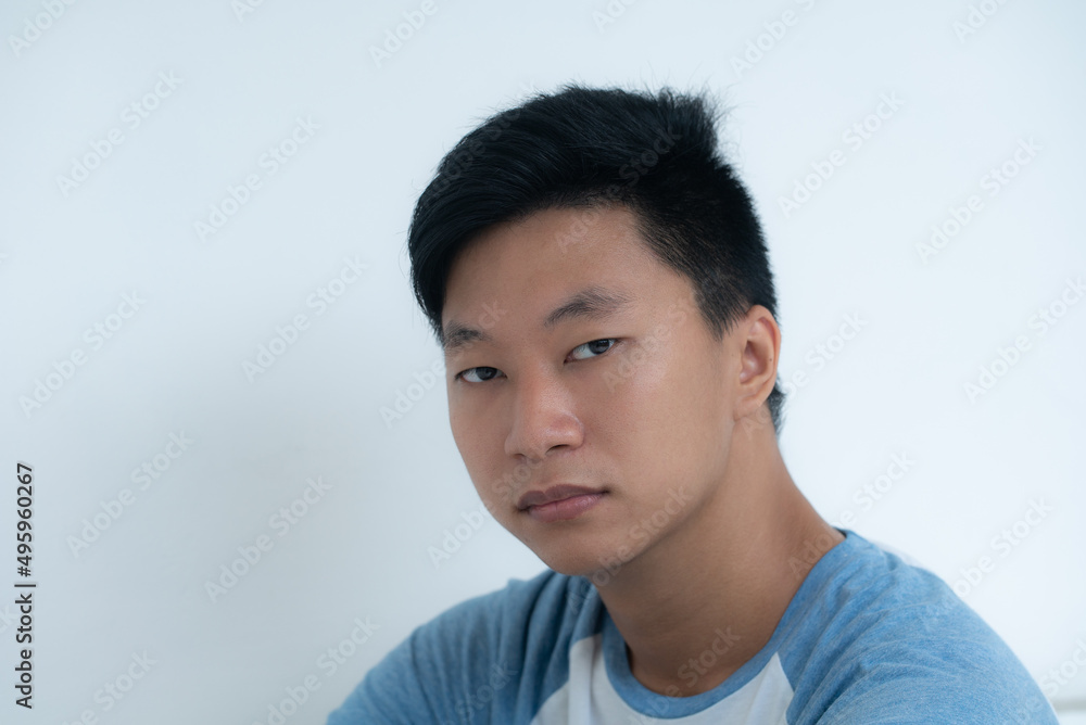 Portrait of young attractive asian man confidently and calmly looks at camera on a white background
