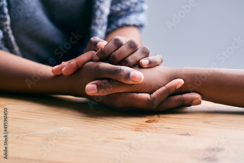 Supporting a friend. Cropped shot of a two people holding hands in comfort on a table. photo