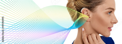 Fotografiet Woman with hearing aid behind the ear with colorful sound waves showing variety of sounds going to the ear