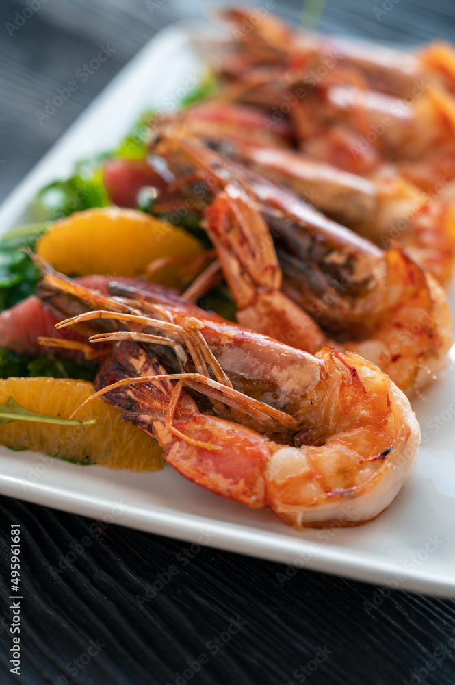 Grilled tiger prawns or shrimps with orange grapefruit and greens on a plate