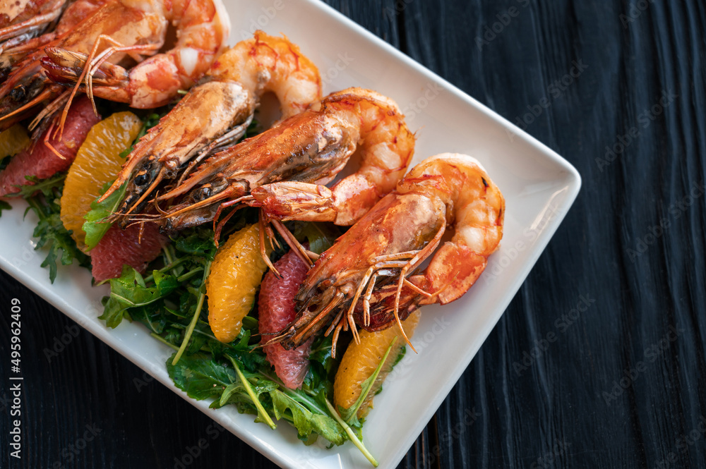 Grilled tiger prawns or shrimps with orange grapefruit and greens on a plate Grilled tiger prawns or shrimps with orange grapefruit and greens on a plate
