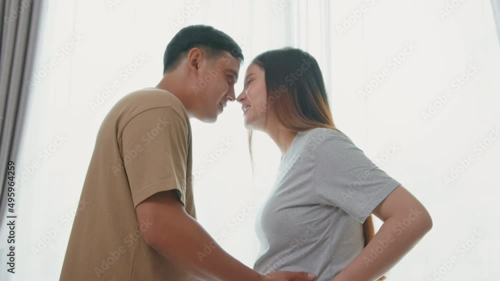 Young pregnant woman with husband embracing and expecting a baby at home Young pregnant woman with husband embracing and expecting a baby at home