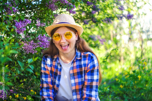 Funny portrait. Defocus beautiful young woman near blooming spring tree. Bush lilac flowers. Youth, love, fashion, romantic, lifestyle concept. Girl in hat nature background. Copy space. Out of focus