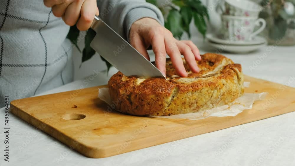 Woman cutting loaf of banana bread in kitchen. Tea party with sweet homemade banana bread cake. Woman cutting loaf of banana bread in kitchen. Tea party with sweet homemade banana bread cake.