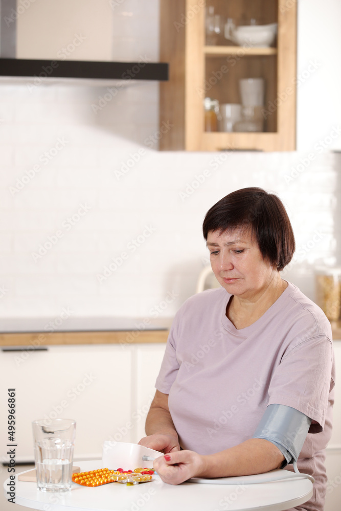 sick older woman take care for health, using sphygmomanometer for measure blood pressure, pulse and heart rate by self and takes medication at home sick older woman take care for health, using sphygmomanometer for measure blood pressure, pulse and heart rate by self and takes medication at home