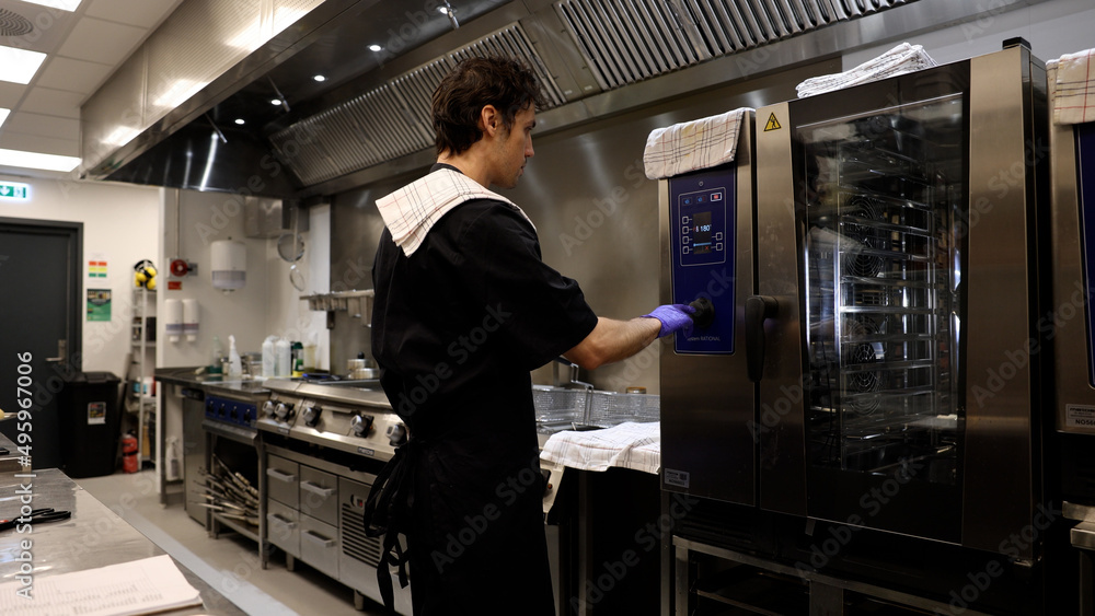 Professional chef in the kitchen of a restaurant. A male chef in a black uniform is working in the kitchen. Slow motion 4K Professional chef in the kitchen of a restaurant. A male chef in a black uniform is working in the kitchen. Slow motion 4K
