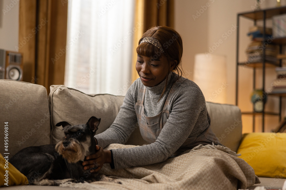 A young girl embraces her dog as they sit together on the couch after a morning walk. The woman enjoys his company and looks at him with concern. Spending time with her pet. A young girl embraces her dog as they sit together on the couch after a morning walk. The woman enjoys his company and looks at him with concern. Spending time with her pet.