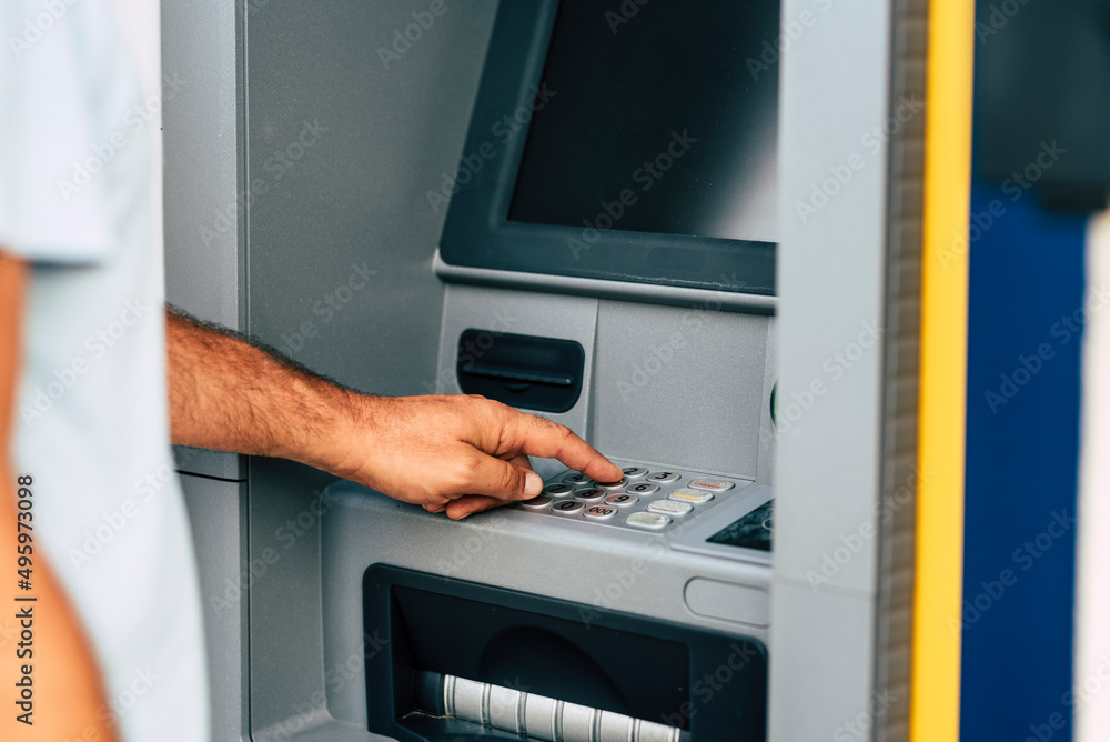 Close up of man hand withdrawing money at automatic atm machine typing secret security code number. Concept of banking activity and business work. People and bank outdoor atm Close up of man hand withdrawing money at automatic atm machine typing secret security code number. Concept of banking activity and business work. People and bank outdoor atm