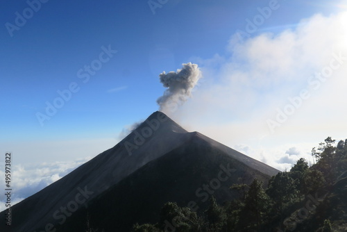 Panorama scene from the breathless Acatenango Volcano in Guatemala in Central America erupting with smoke and lava on a sunny day with a blue sky 