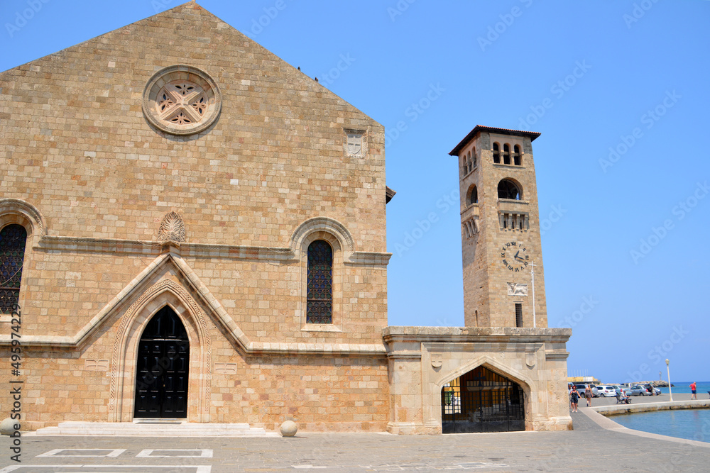 brick square with ancient church and tower with clock in Rhodes, Greece