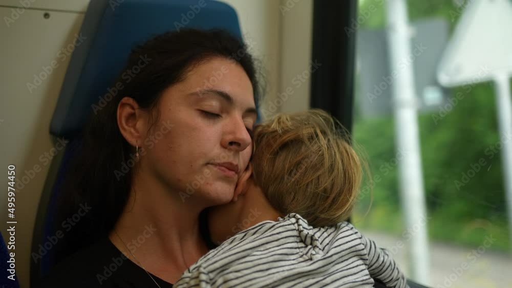 Tired mother traveling by train carrying child asleeep Tired mother traveling by train carrying child asleeep