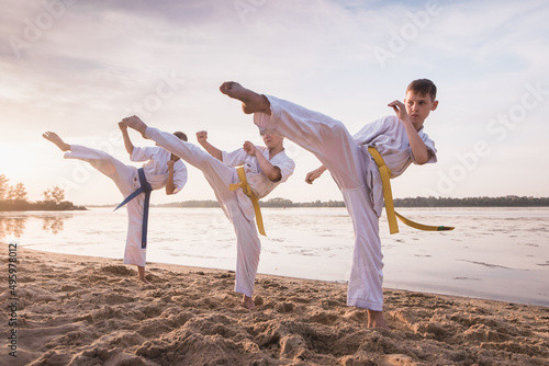 Canvas Print Children karate section training on beach sand near the river