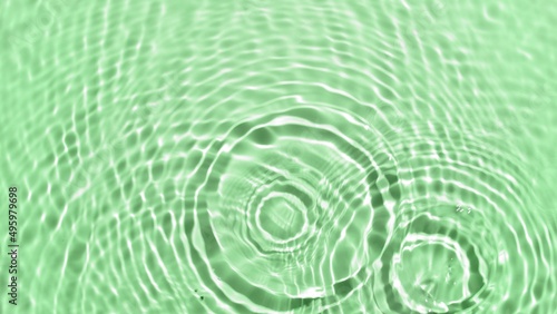 Several drops makes wave circles on water surface over pale green background | Background shot skin care products