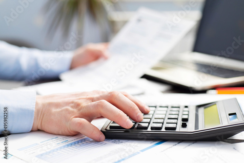 Man with bills and calculator. Businessman using calculator to calculate bills at the table in office. Financial accounting concept