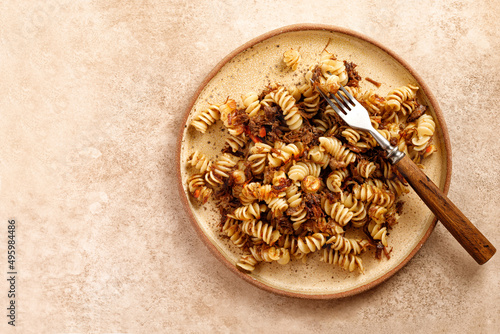 Spiral pasta with stew beef on plate and beige background. Pasta Russian Navy Style. Fusilli