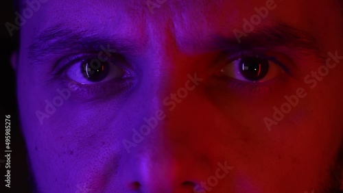 Face portrait of young man on neon light. Macro close up shot of eye, emotional cool guy with studio light.