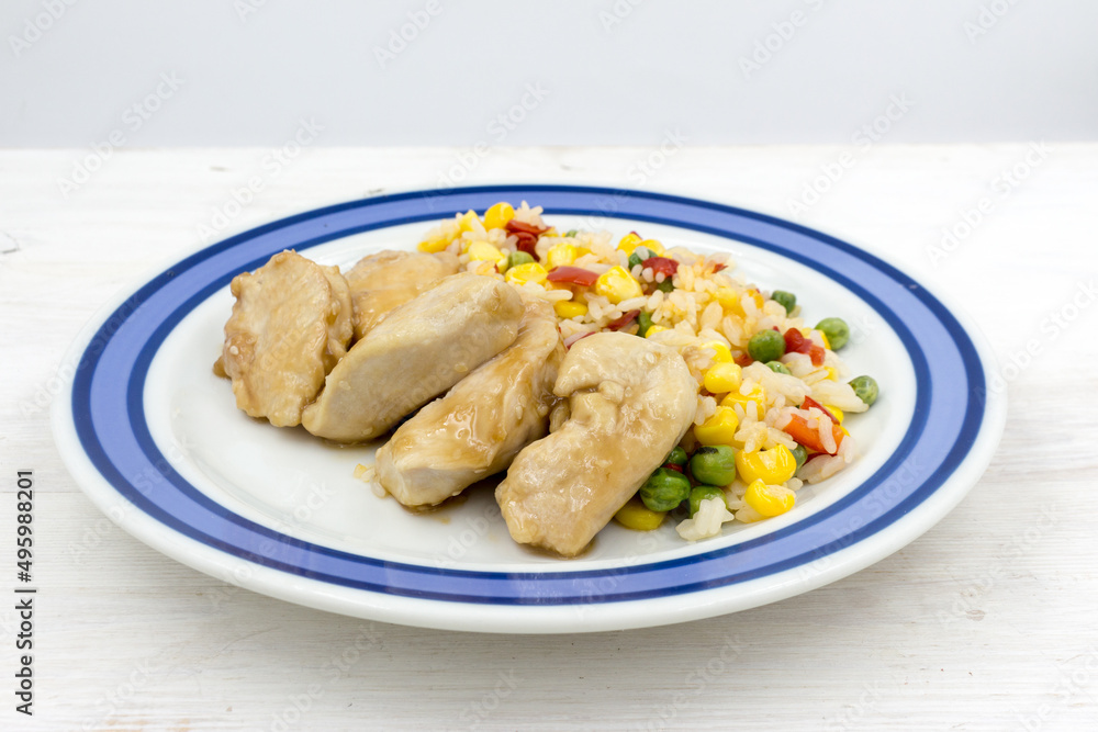 Chicken chops with rice and vegetables on a wooden table Chicken chops with rice and vegetables on a wooden table