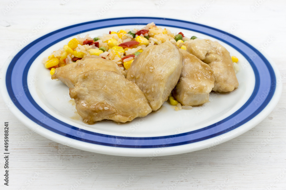 Chicken chops with rice and vegetables on a wooden table