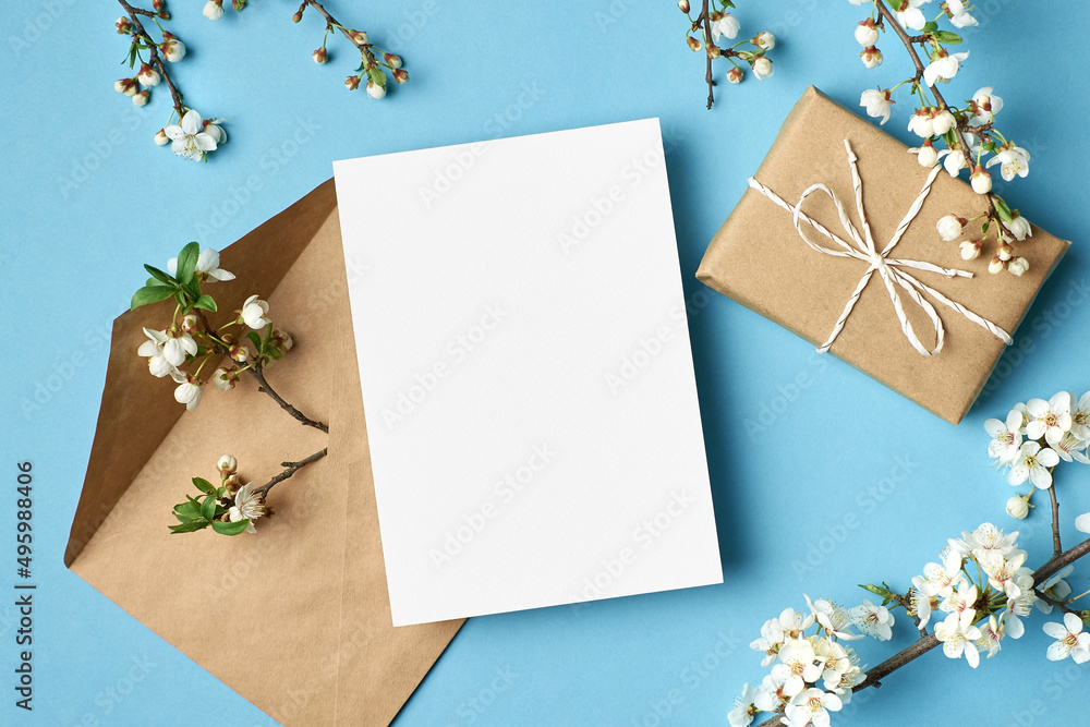 Greeting card mockup with gift, envelope and white flowers on blue Greeting card mockup with gift, envelope and white flowers on blue