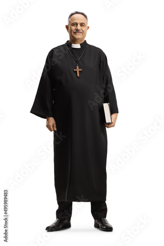 Full length portrait of a priest walking holding a bible and smiling at camera Fototapet
