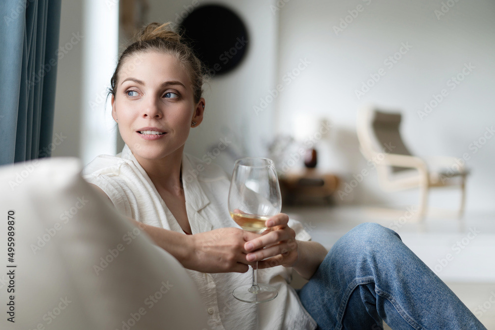Successful young beautiful woman sitting on a sofa in the living room, drinking wine Successful young beautiful woman sitting on a sofa in the living room, drinking wine