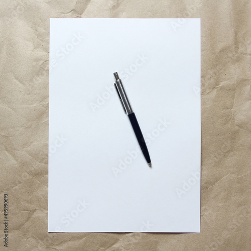 White empty sheet of A4 format with pen on a beige craft paper. Concept of analysis, study, attentive work. Stock photo with empty place for your text and design.