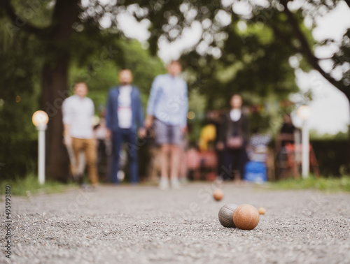 Friends playing petanque in city park on bocce court guy through a ball vintage