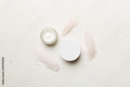 Spa cosmetic product, cream jar, branding mock up, top view with feathers background. Flat lay