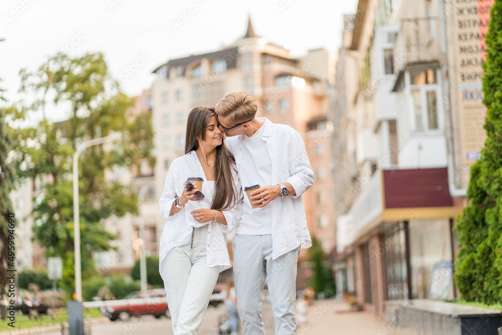 guy with a girl in white clothes walks around the city and drinks coffee guy with a girl in white clothes walks around the city and drinks coffee