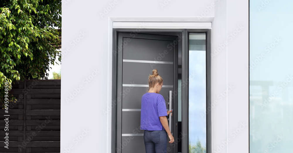 Fototapeta premium Beautiful woman opening the door of her home.