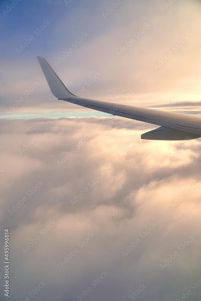 Flying and traveling. View of airplane wing during sunset. Plane over clouds in the sky.