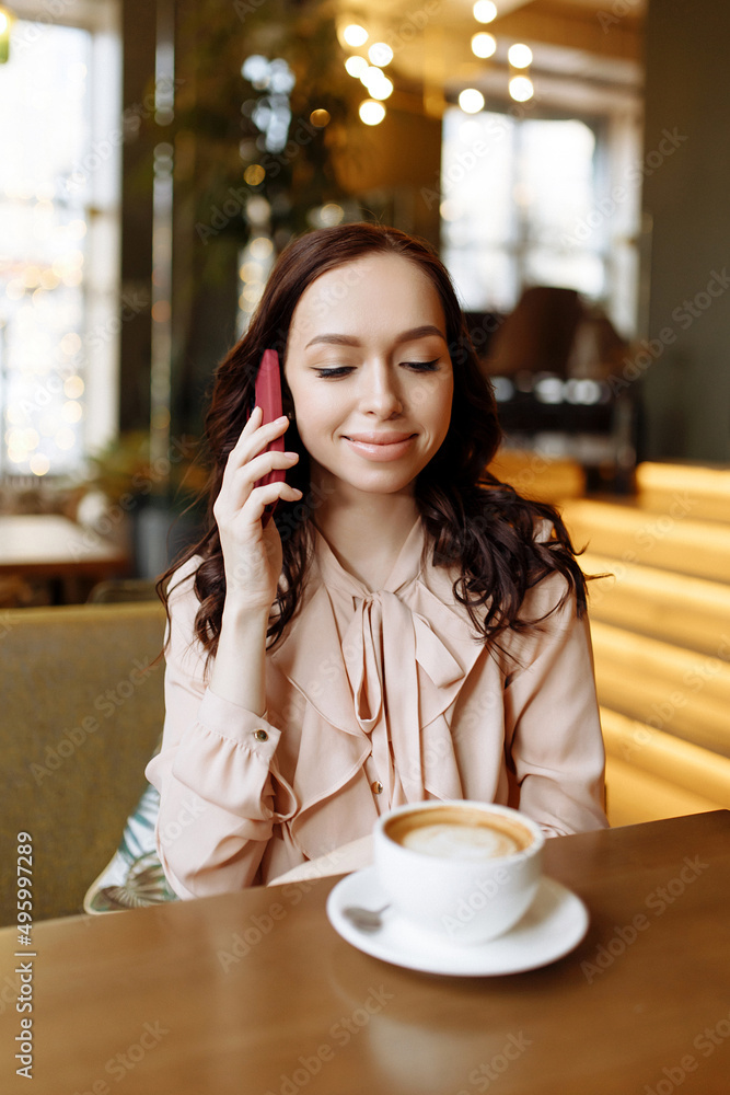 Beautiful young girl calls on the phone in a cafe. Beautiful young girl calls on the phone in a cafe.