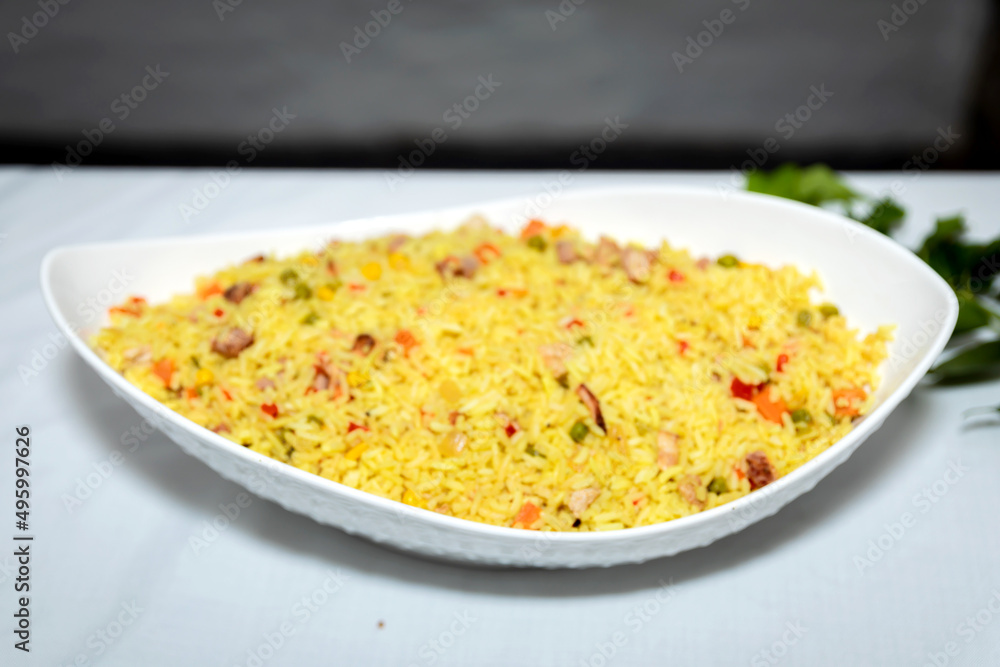 Aromatic yellow rice served in a square white server Aromatic yellow rice served in a square white server