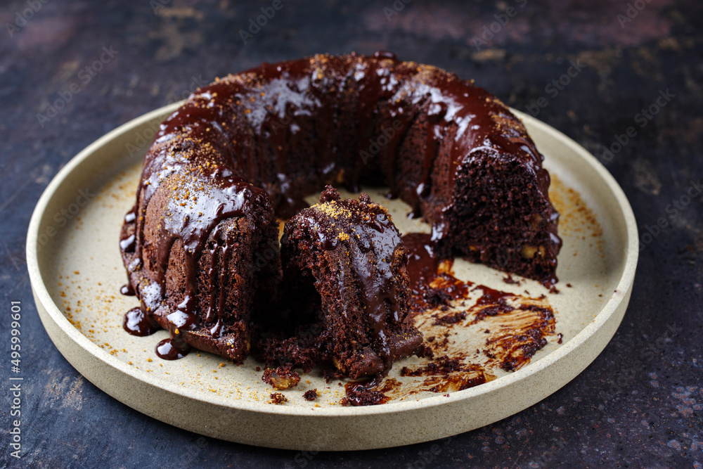 Traditional chocolate bundt cake with icing glaze topping and muscovado brown sugar served as close-up on a plate Traditional chocolate bundt cake with icing glaze topping and muscovado brown sugar served as close-up on a plate