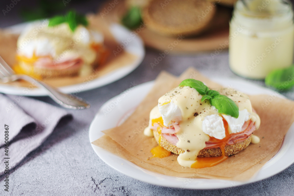 Egg benedict sandwiches - muffin with poached egg, ham and hollandaise sauce Egg benedict sandwiches - muffin with poached egg, ham and hollandaise sauce